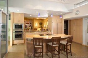 A luxury kitchen with lots of natural light, an open-plan design, and light wood kitchen cabinets.