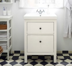 A white wash-stand on a chequered black and white tile floor.