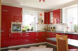 Simple all-red modern kitchen with small dine-in table and chairs