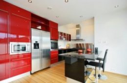Small red kitchen with black island and light hard wood flooring