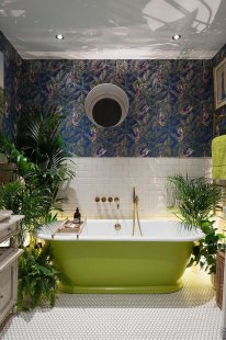 Wallpaper and plants create a jungle-inspired environment inside the eclectic bathroom